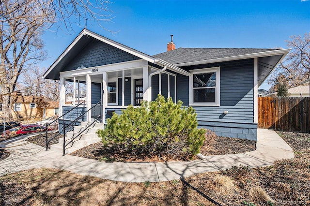 bungalow-style house with a chimney, roof with shingles, and fence