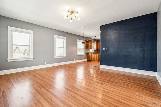 unfurnished living room with light wood-type flooring and baseboards