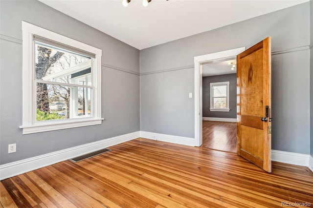 empty room featuring visible vents, light wood-style flooring, and baseboards