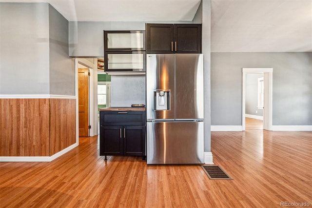 kitchen with visible vents, a wainscoted wall, stainless steel fridge with ice dispenser, light wood finished floors, and baseboards