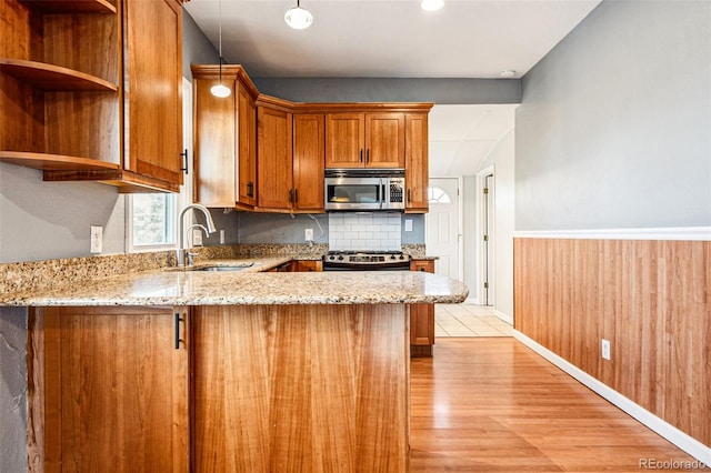 kitchen with stainless steel microwave, gas stove, light stone countertops, and a sink