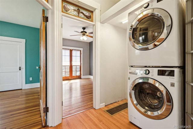 laundry room featuring visible vents, baseboards, laundry area, light wood-style flooring, and stacked washer and dryer