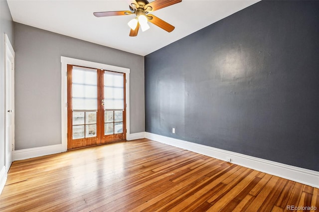 spare room featuring wood finished floors, french doors, baseboards, and ceiling fan