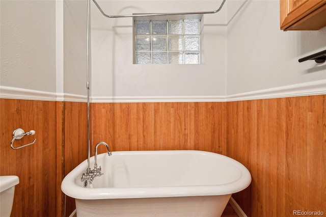 full bathroom with a freestanding bath, wood walls, and wainscoting