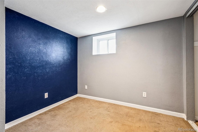 empty room with a textured wall, baseboards, and carpet floors