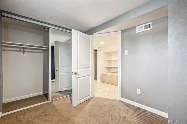 unfurnished bedroom featuring light colored carpet, visible vents, a closet, and baseboards