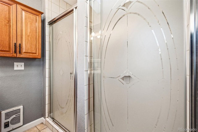 bathroom featuring tile patterned flooring, heating unit, a textured wall, and a marble finish shower