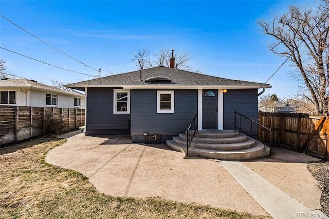 rear view of house featuring a patio area, a fenced backyard, a chimney, and a shingled roof