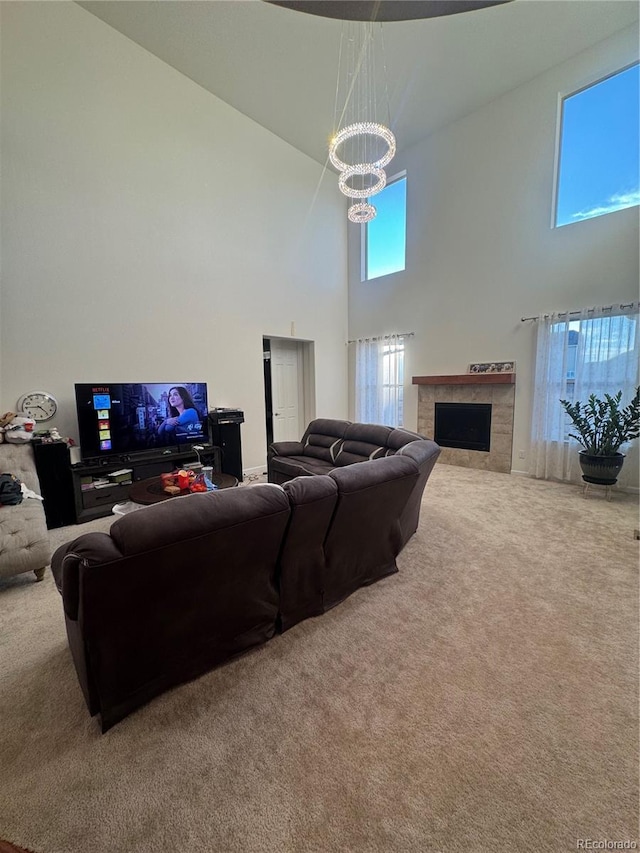 carpeted living room with a towering ceiling, a tile fireplace, and a notable chandelier