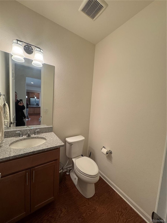 bathroom with wood-type flooring, toilet, and vanity