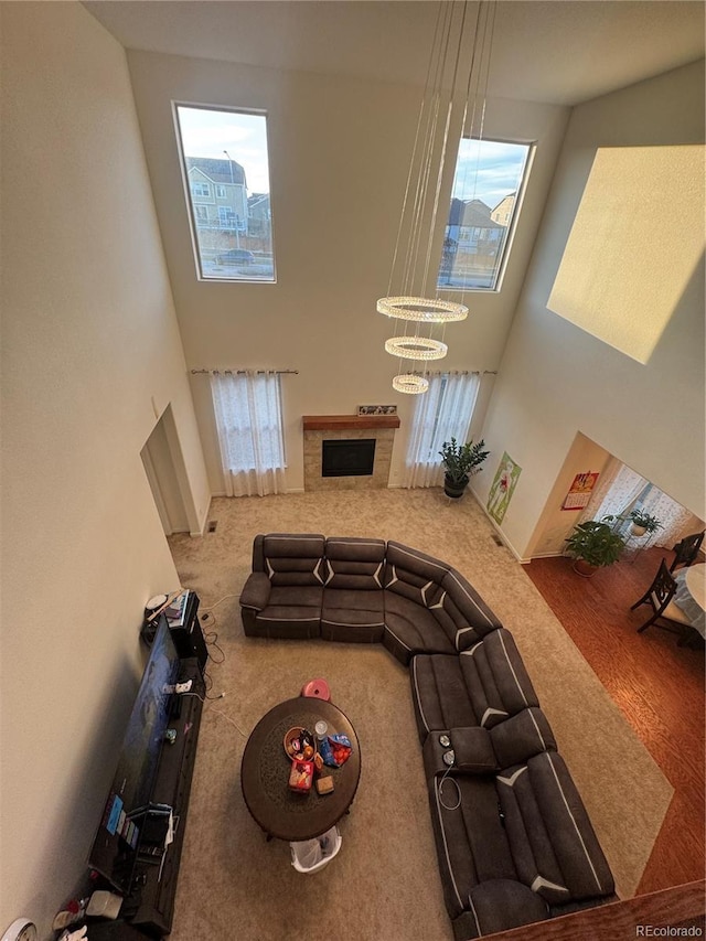 living room with an inviting chandelier, a towering ceiling, and carpet