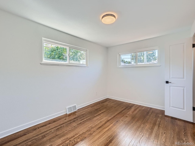 empty room with dark hardwood / wood-style floors and a healthy amount of sunlight