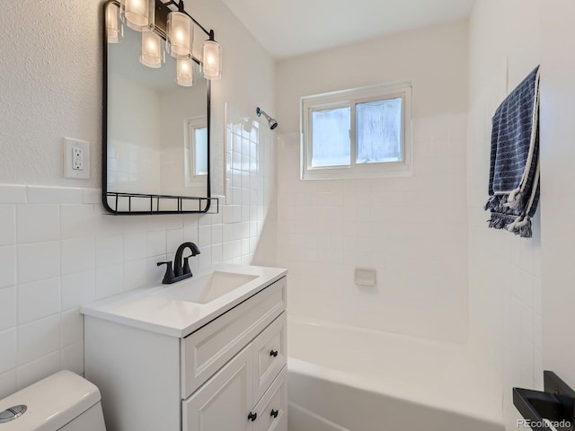 full bathroom with tiled shower / bath combo, vanity, toilet, and tile walls