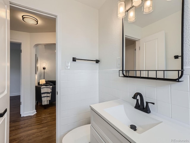 bathroom with toilet, hardwood / wood-style floors, vanity, tasteful backsplash, and tile walls