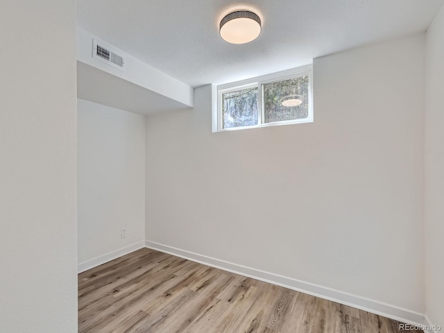 basement featuring a textured ceiling and light hardwood / wood-style flooring