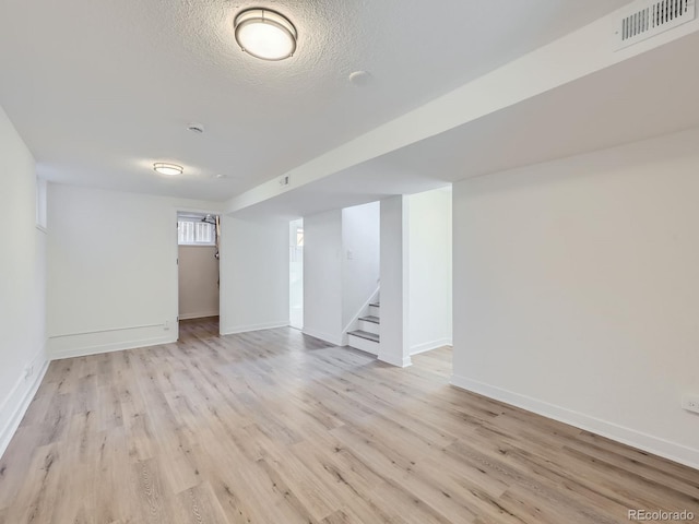 basement featuring a textured ceiling and light wood-type flooring