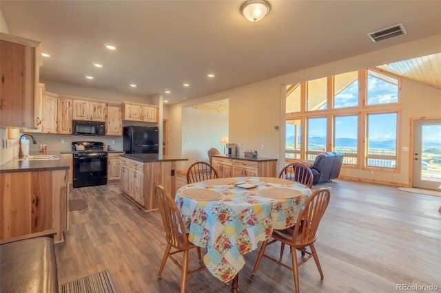 dining space featuring light hardwood / wood-style floors, sink, and vaulted ceiling