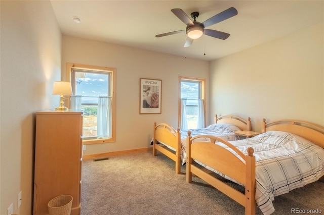 carpeted bedroom featuring multiple windows and ceiling fan