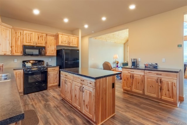 kitchen featuring dark wood-style floors, a center island, dark countertops, black appliances, and light brown cabinetry