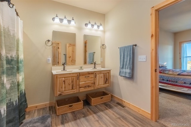 ensuite bathroom featuring a sink, baseboards, connected bathroom, and wood finished floors