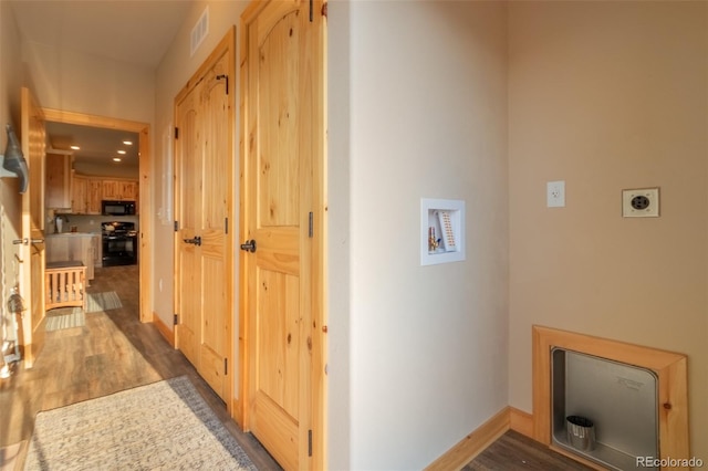 hallway with visible vents, baseboards, and wood finished floors