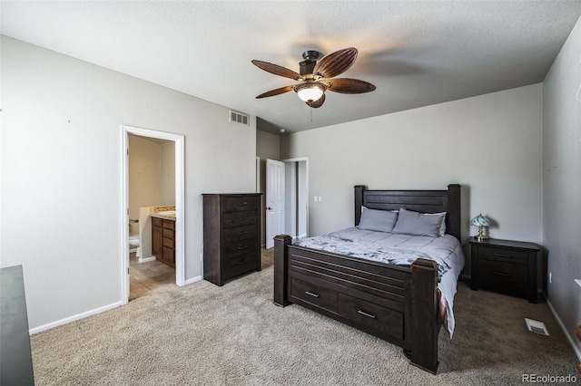 bedroom featuring light carpet, baseboards, visible vents, ensuite bath, and ceiling fan