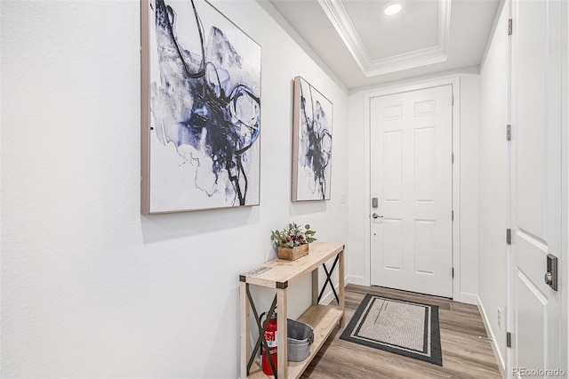 foyer featuring wood finished floors, baseboards, a tray ceiling, recessed lighting, and ornamental molding