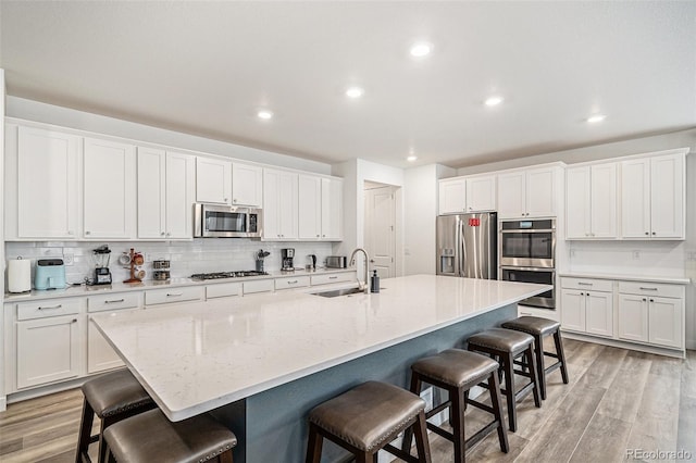 kitchen featuring white cabinetry, sink, a kitchen breakfast bar, and appliances with stainless steel finishes