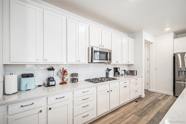 kitchen with white cabinetry, light stone countertops, and appliances with stainless steel finishes