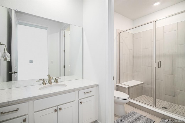 bathroom featuring tile patterned floors, vanity, toilet, and a shower with shower door