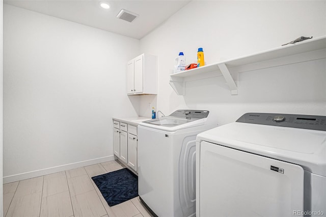 clothes washing area featuring cabinets and washing machine and dryer