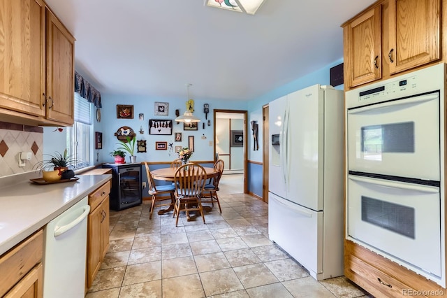kitchen with brown cabinets, white appliances, beverage cooler, light countertops, and tasteful backsplash