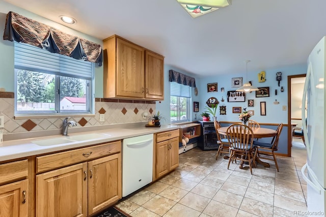 kitchen featuring a sink, backsplash, white appliances, and light countertops