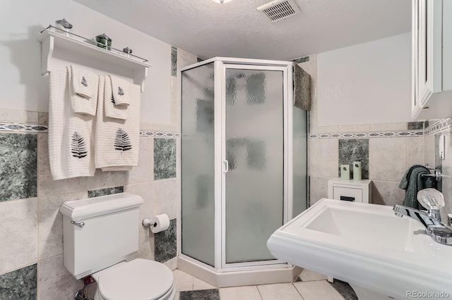 full bathroom featuring tile walls, a shower stall, toilet, and visible vents