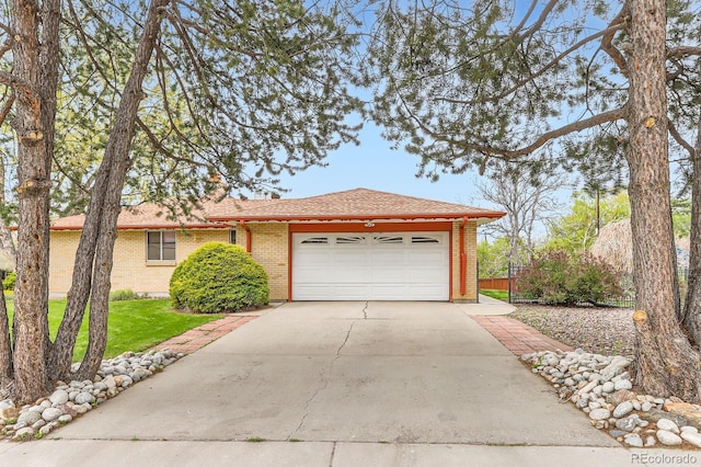 view of front of house featuring fence, roof with shingles, brick siding, an attached garage, and driveway