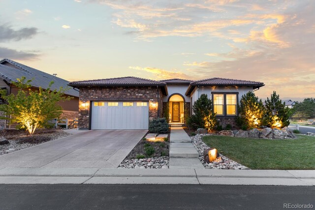 10660 Winding Pine Pt, Highlands Ranch, CO 80126 - mediterranean / spanish-style house featuring stone siding, an attached garage, a tiled roof, concrete driveway, and a yard