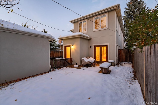 snow covered back of property featuring french doors