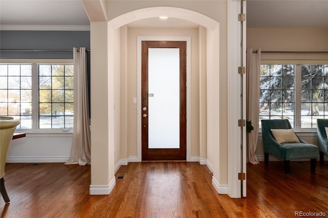 foyer with wood-type flooring and crown molding