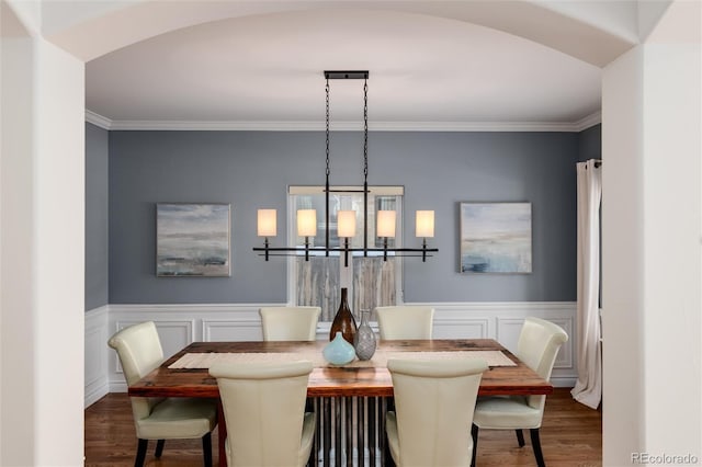 dining space with dark hardwood / wood-style flooring, ornamental molding, and an inviting chandelier