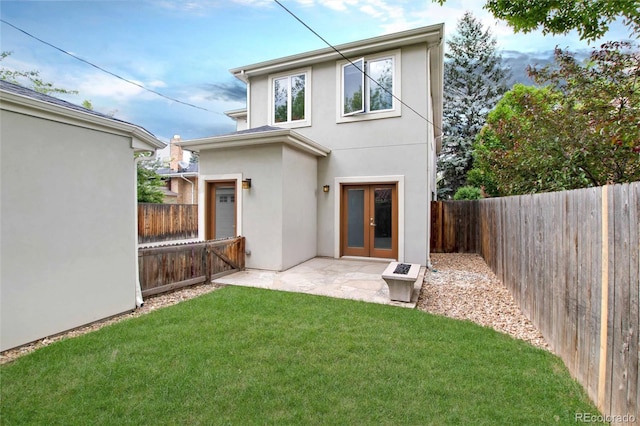 rear view of property with a yard, french doors, a fenced backyard, and stucco siding