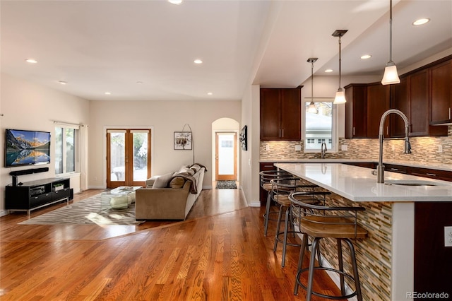 kitchen featuring a kitchen breakfast bar, a sink, pendant lighting, decorative backsplash, and open floor plan