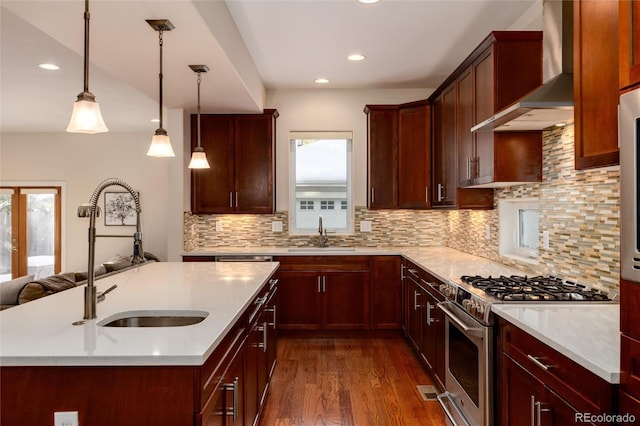 kitchen with high end stainless steel range, wall chimney range hood, recessed lighting, and a sink