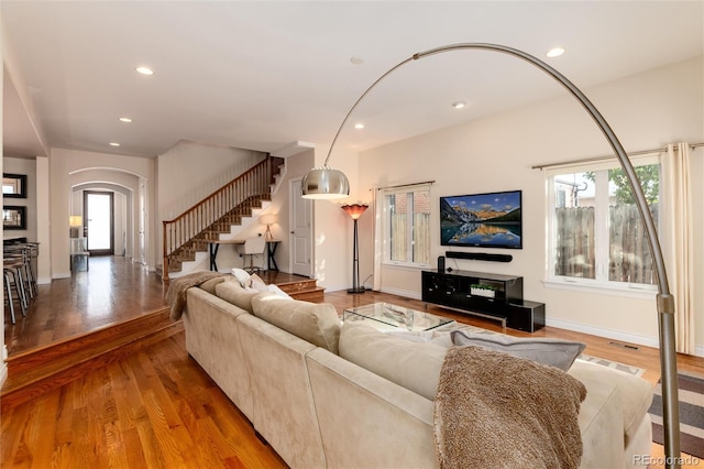 living room featuring arched walkways, a healthy amount of sunlight, stairs, and recessed lighting
