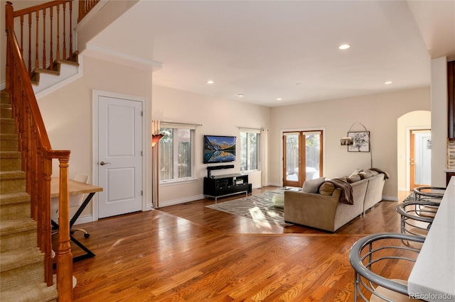living room with arched walkways, stairs, wood finished floors, and recessed lighting