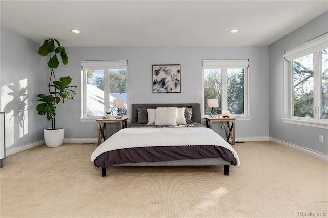 bedroom with baseboards, light colored carpet, and multiple windows