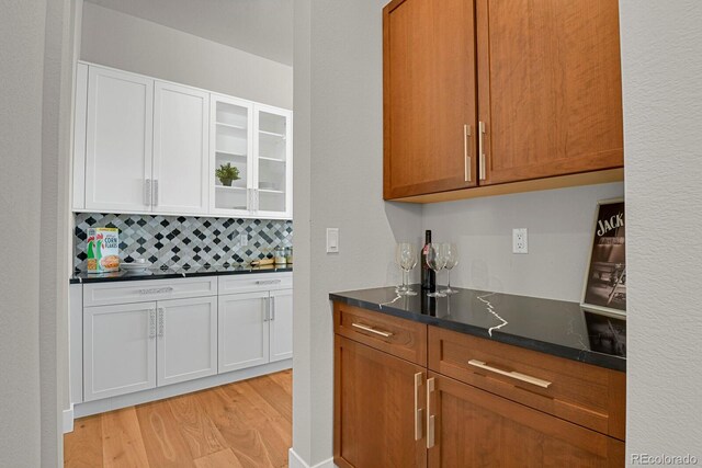 kitchen with tasteful backsplash, light hardwood / wood-style flooring, and white cabinets