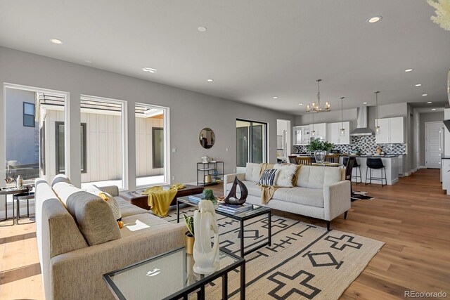 living room featuring plenty of natural light, an inviting chandelier, and light hardwood / wood-style floors