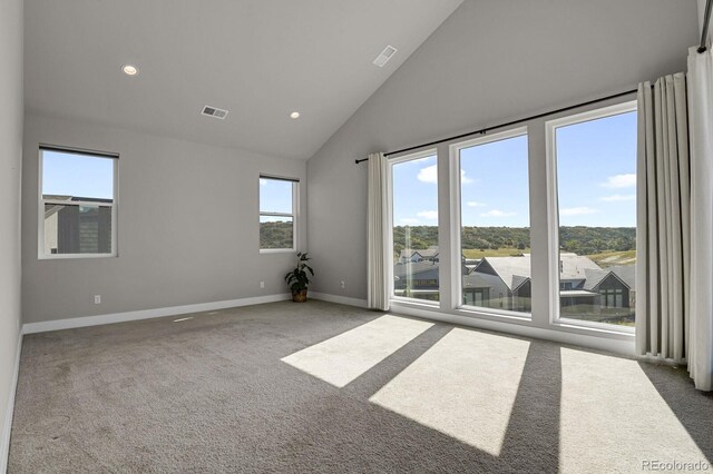 carpeted spare room featuring high vaulted ceiling