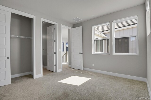 unfurnished bedroom with light colored carpet and a closet