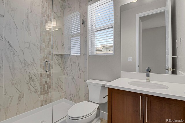 bathroom with vanity, toilet, a healthy amount of sunlight, and a shower with door